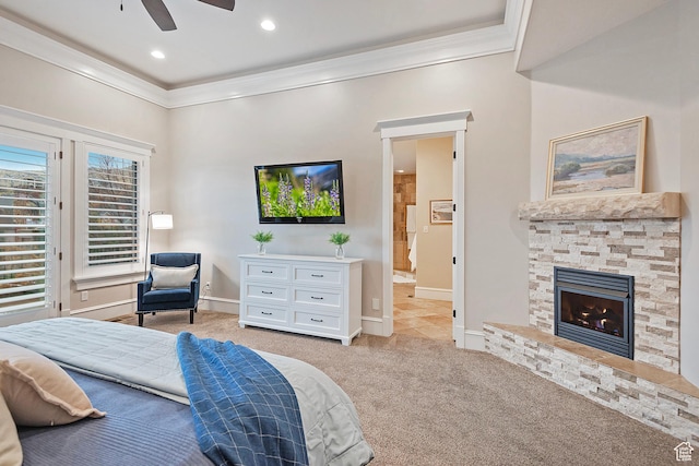 bedroom with crown molding, light carpet, baseboards, a stone fireplace, and ensuite bathroom