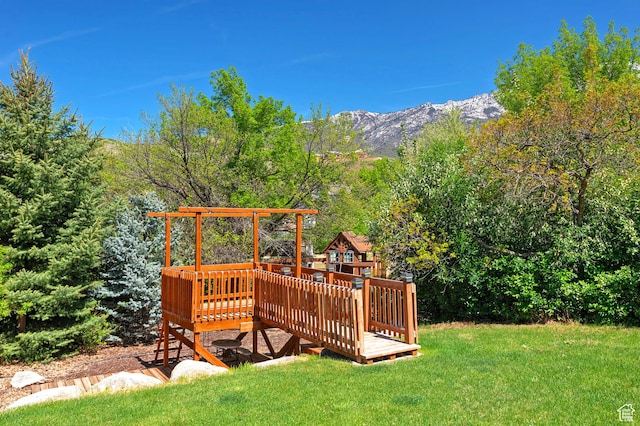 view of green lawn with a deck with mountain view