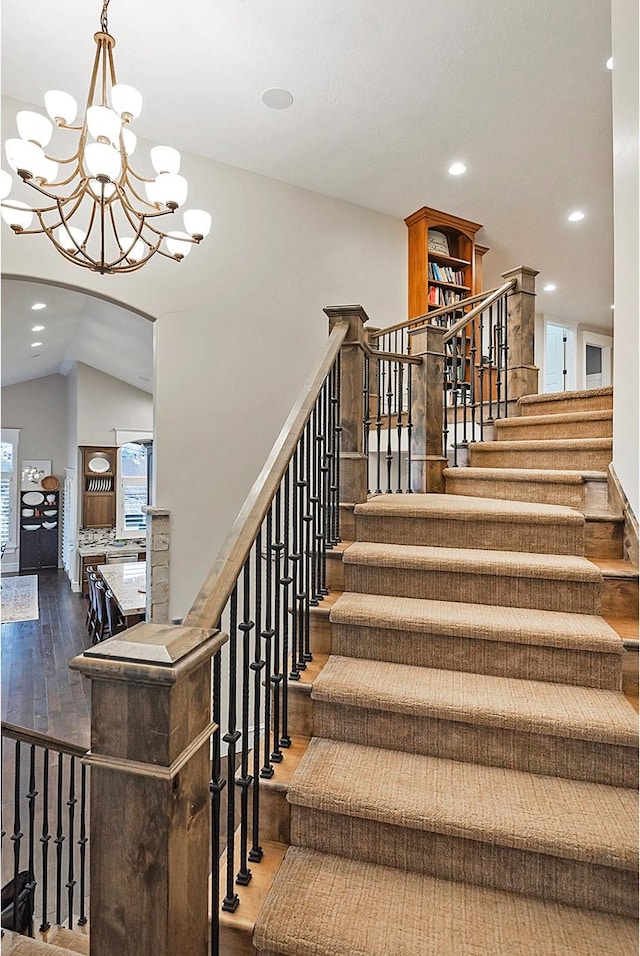 stairs featuring hardwood / wood-style flooring, a chandelier, recessed lighting, and lofted ceiling