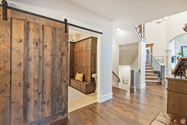 foyer entrance with hardwood / wood-style flooring, a barn door, arched walkways, and stairway