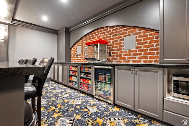 wine room featuring wine cooler, ornamental molding, a community bar, and carpet floors