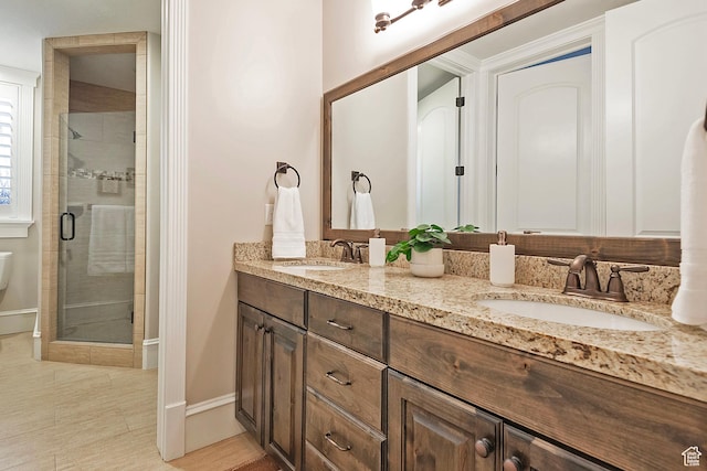 full bathroom featuring a stall shower, double vanity, and baseboards
