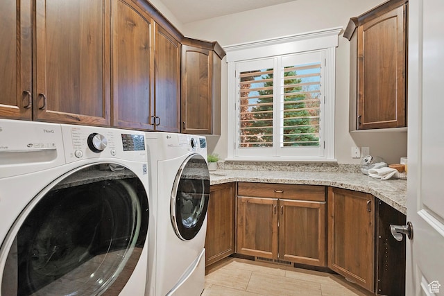 laundry room featuring cabinet space, washer and clothes dryer, and light tile patterned floors