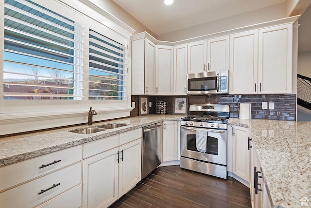 kitchen with appliances with stainless steel finishes, a sink, tasteful backsplash, white cabinetry, and recessed lighting