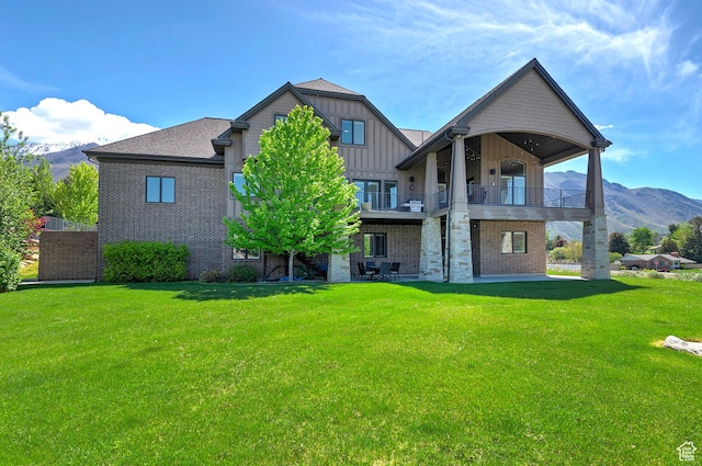 back of property featuring a mountain view, a lawn, and a balcony