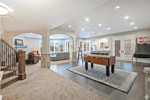 game room featuring arched walkways, recessed lighting, dark wood-style flooring, and french doors