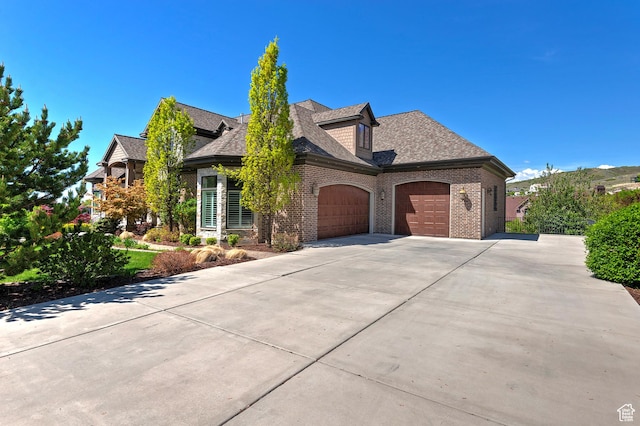 view of front of house with a garage, brick siding, driveway, and a shingled roof