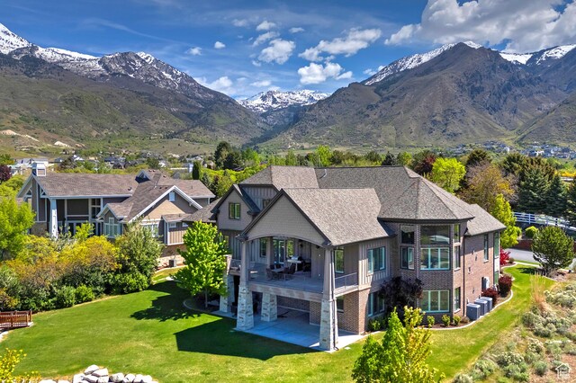 rear view of house featuring a patio, a lawn, central AC, and a mountain view