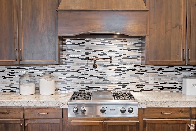 kitchen featuring stainless steel gas stovetop, decorative backsplash, light countertops, and dark brown cabinets