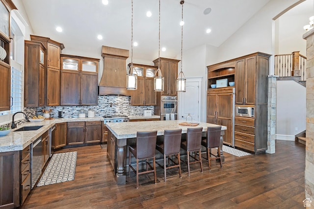 kitchen with appliances with stainless steel finishes, a kitchen island, open shelves, a sink, and dark wood-type flooring