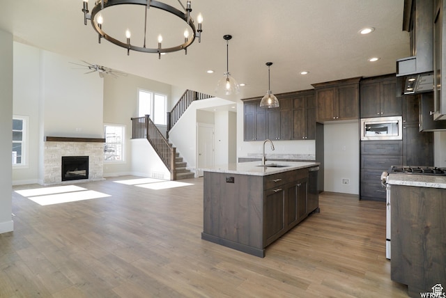kitchen featuring a sink, stainless steel appliances, dark brown cabinetry, light wood-style floors, and decorative light fixtures
