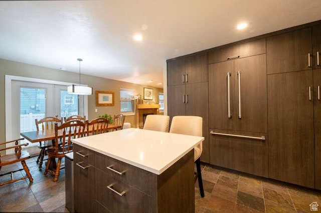 1689 E Kierstin Pl, Salt Lake City, UT 84108 - kitchen with stone tile floors, a breakfast bar, light countertops, decorative light fixtures, and a center island
