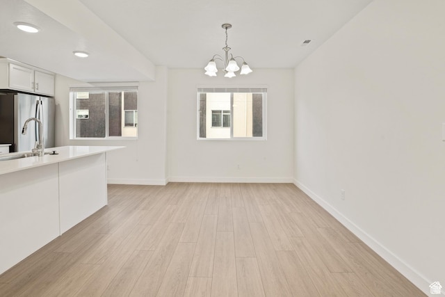 67 E Hamblin Ln, Clearfield, UT 84015 - unfurnished dining area with light wood finished floors, a chandelier, healthy amount of natural light, and recessed lighting