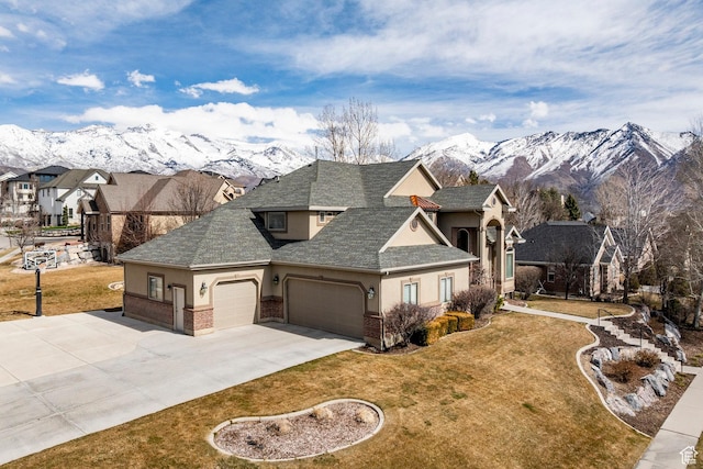 view of front of house featuring a garage, a front lawn, a mountain view, and stucco siding