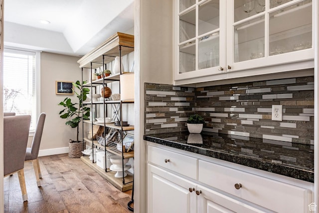 bar featuring light wood-style floors, baseboards, and decorative backsplash