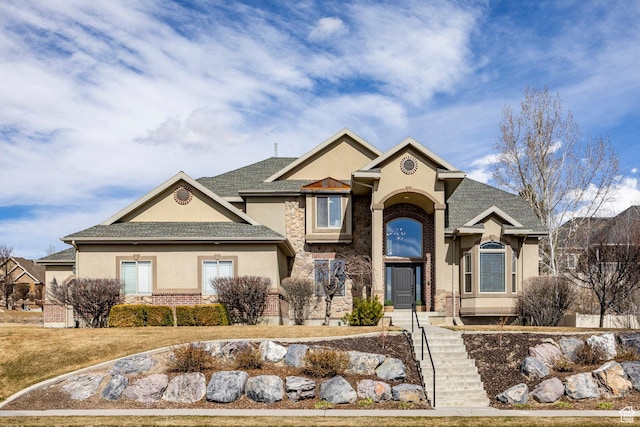 traditional-style home with stucco siding, brick siding, and a shingled roof