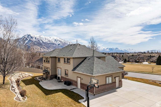 exterior space with a mountain view, fence, a lawn, a patio, and stucco siding