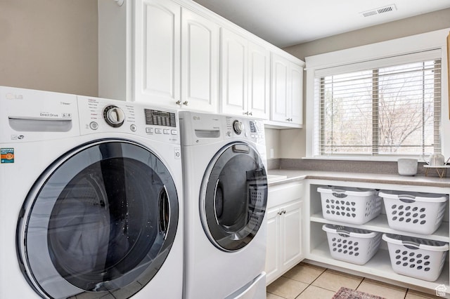 clothes washing area featuring cabinet space, washer and clothes dryer, visible vents, and light tile patterned floors