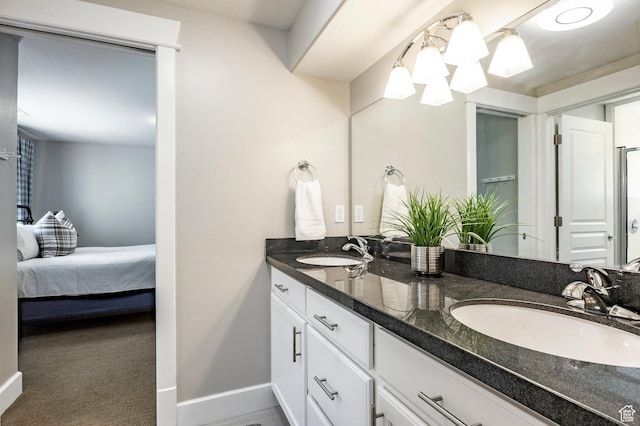 ensuite bathroom featuring baseboards, a sink, double vanity, and connected bathroom