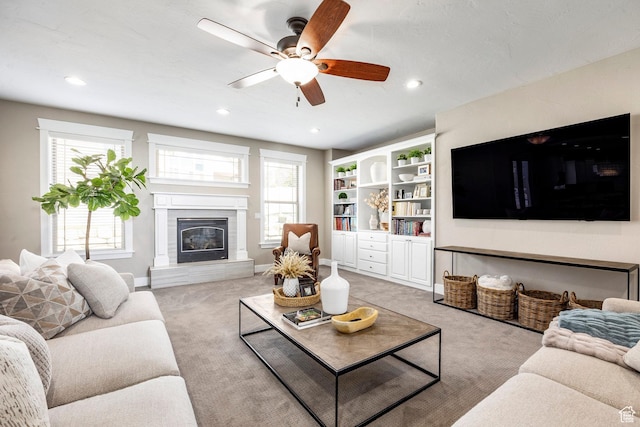 living room featuring light colored carpet, a wealth of natural light, a ceiling fan, and a glass covered fireplace