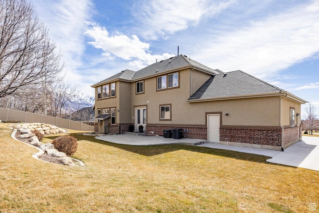 rear view of house featuring stucco siding, brick siding, fence, and a patio