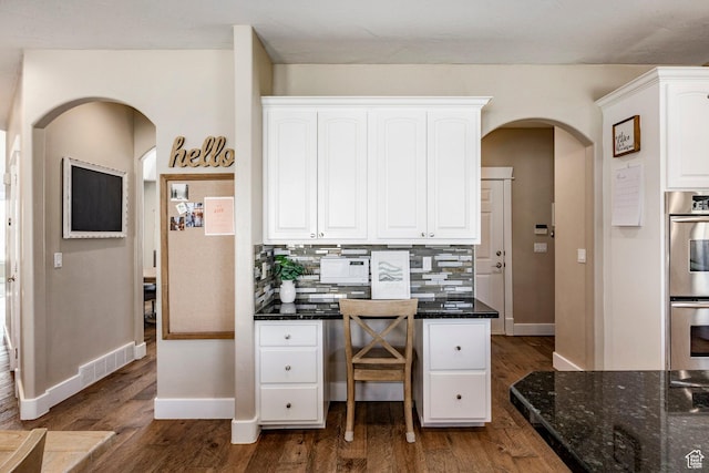 office area featuring dark wood-style floors, arched walkways, visible vents, and baseboards