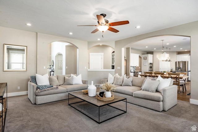 carpeted living room with arched walkways, ceiling fan, baseboards, and recessed lighting