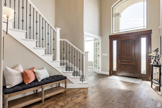 foyer with baseboards, hardwood / wood-style flooring, a high ceiling, and stairway
