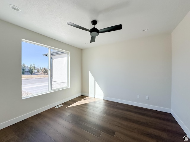 spare room featuring dark wood-style flooring, baseboards, a textured ceiling, ceiling fan, and visible vents