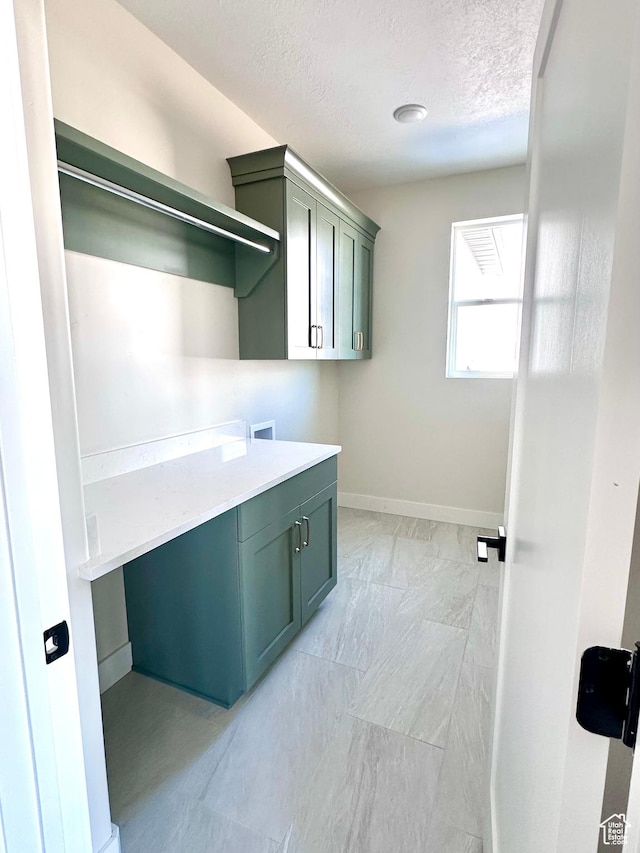 washroom with cabinet space, a textured ceiling, baseboards, and washer hookup