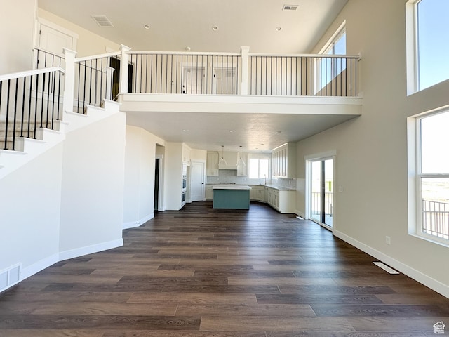 unfurnished living room featuring dark wood-style flooring, baseboards, and visible vents