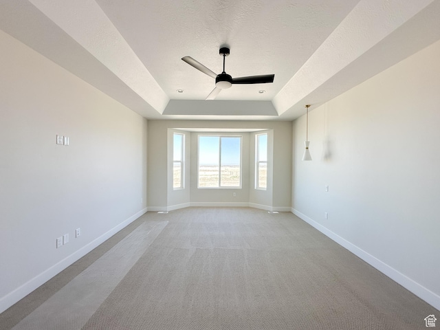 spare room featuring baseboards, a textured ceiling, ceiling fan, and a raised ceiling