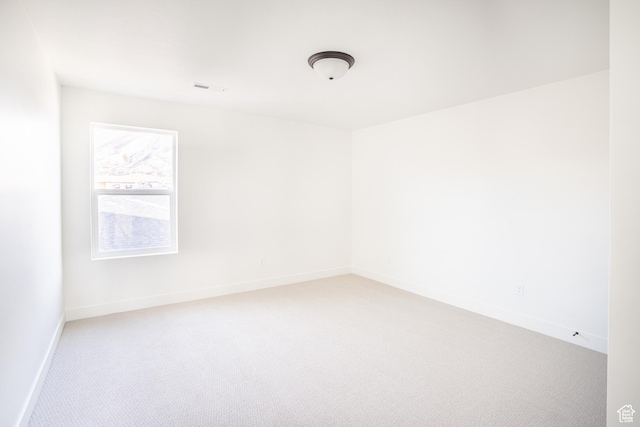 spare room featuring visible vents, baseboards, and light carpet