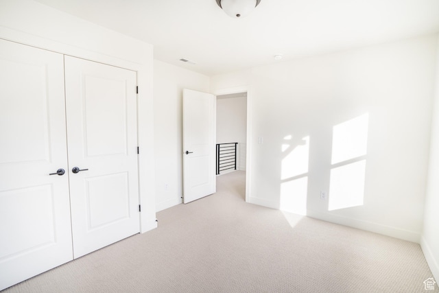 unfurnished bedroom with light carpet, a closet, baseboards, and visible vents