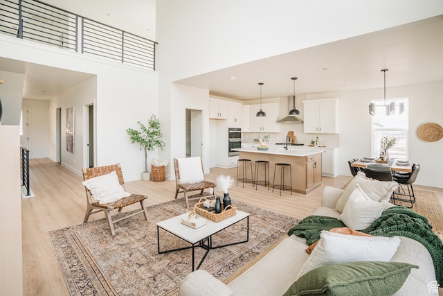 living room with light wood-style flooring, a high ceiling, and baseboards