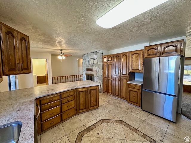 kitchen featuring a ceiling fan, a textured ceiling, freestanding refrigerator, a peninsula, and light countertops