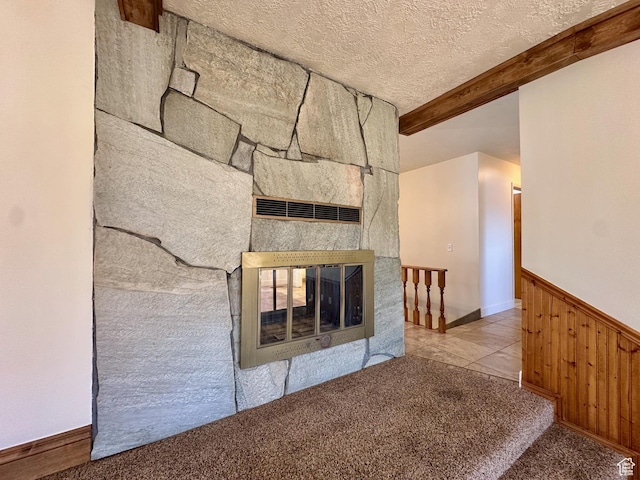 interior details featuring a textured ceiling, wooden walls, carpet floors, beam ceiling, and wainscoting