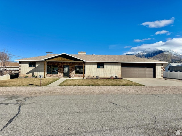 view of front of property with driveway, fence, an attached garage, a front yard, and brick siding
