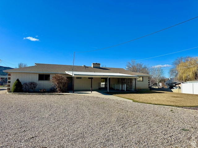 rear view of property featuring brick siding, a lawn, fence, and a chimney