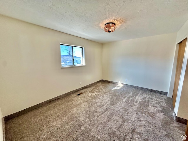 unfurnished room with baseboards, carpet flooring, a textured ceiling, and visible vents