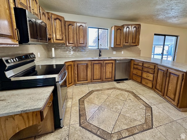 kitchen with a sink, brown cabinets, tasteful backsplash, and appliances with stainless steel finishes