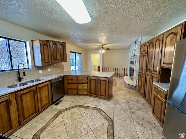 kitchen featuring a peninsula, plenty of natural light, stainless steel appliances, and a sink