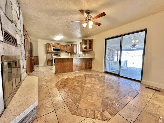 kitchen with a ceiling fan, visible vents, baseboards, a peninsula, and appliances with stainless steel finishes