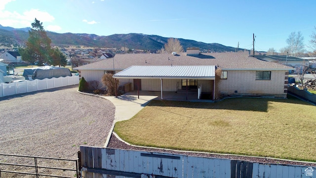 back of property featuring brick siding, a fenced backyard, a lawn, a patio area, and a mountain view