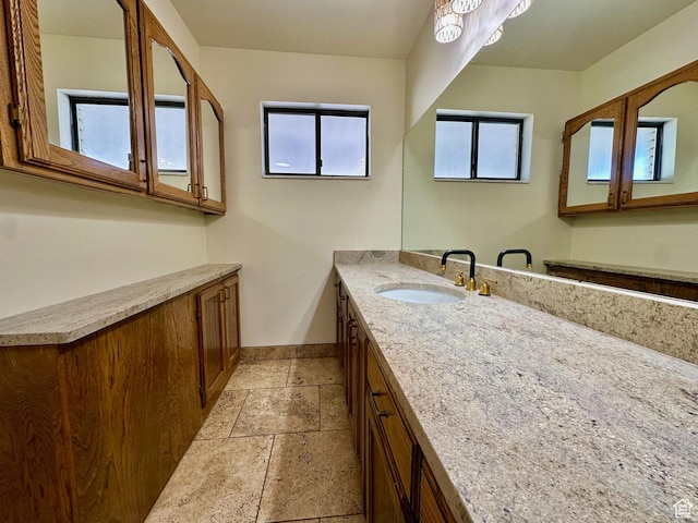 bathroom with vanity, stone tile floors, and baseboards