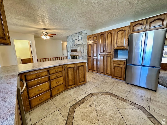 kitchen with a textured ceiling, light countertops, freestanding refrigerator, and a ceiling fan