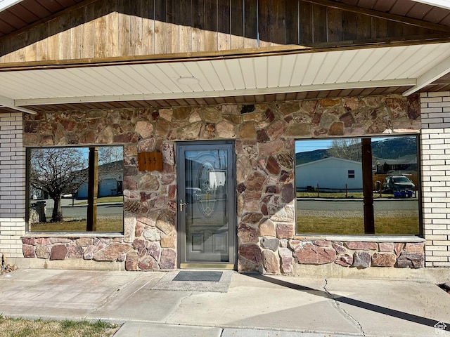 entrance to property featuring brick siding and stone siding