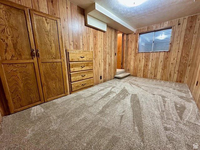 interior space with wooden walls, carpet flooring, and a textured ceiling