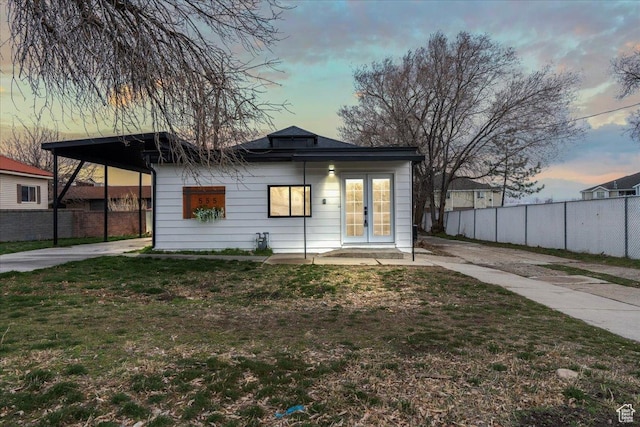bungalow-style house with french doors, a yard, driveway, and fence