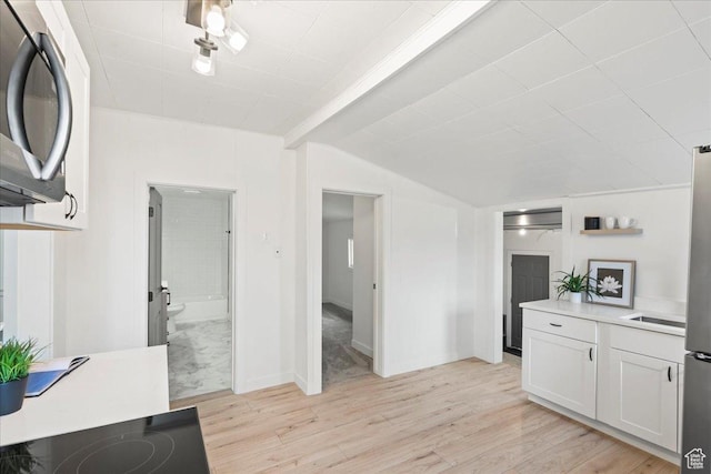 555 N 100 W, Tooele, UT 84074 - kitchen featuring light wood-style flooring, light countertops, vaulted ceiling, white cabinetry, and stainless steel microwave